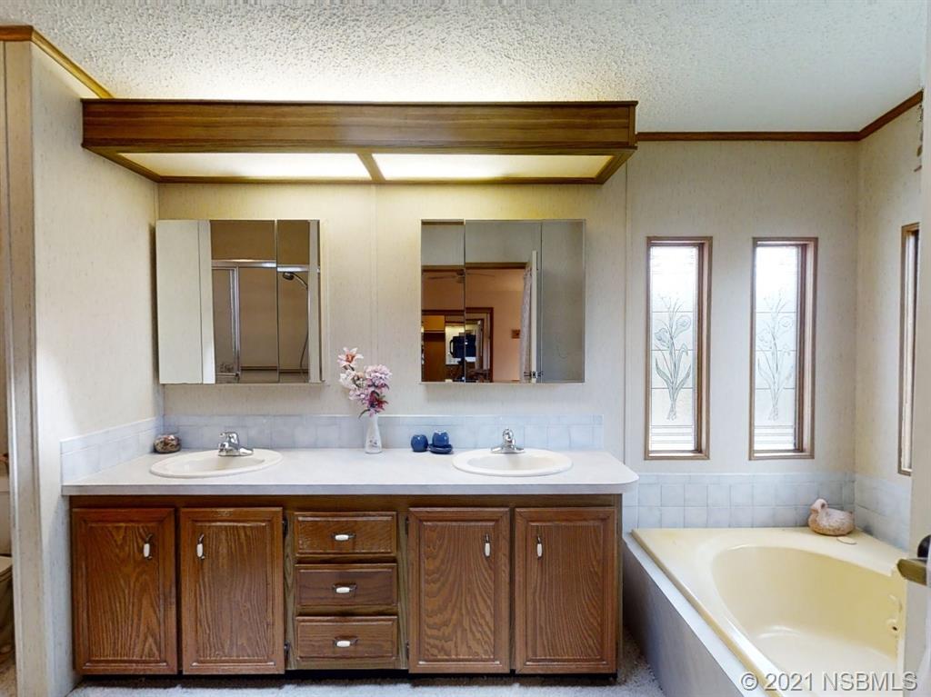 705 Navigators Way Edgewater, FL 32141 - Photo 7 of 33 a bathroom with a granite countertop tub double vanity sink and a large mirror