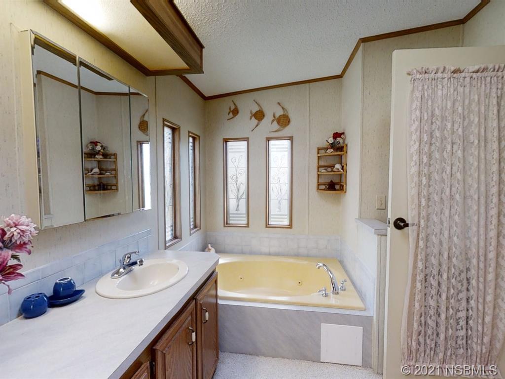 705 Navigators Way Edgewater, FL 32141 - Photo 9 of 33 a bathroom with a tub sink and mirror