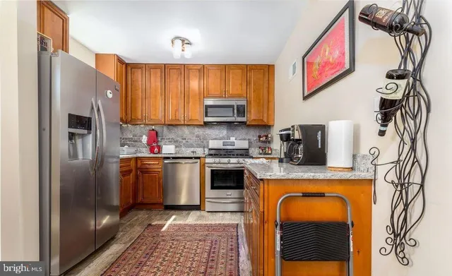 a kitchen with stainless steel appliances granite countertop a refrigerator a stove and a sink