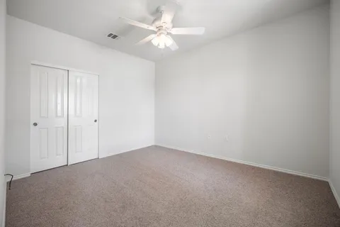 an empty room with windows and fan