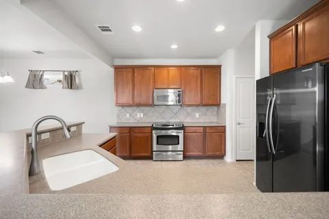 a kitchen with stainless steel appliances granite countertop a refrigerator sink and stove