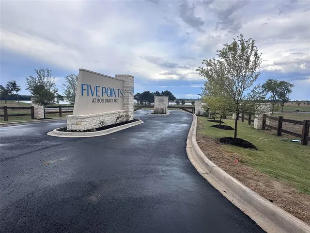 a view of a street with a bench and large trees
