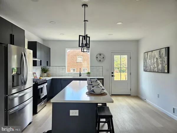 a kitchen with stainless steel appliances a dining table chairs refrigerator and sink