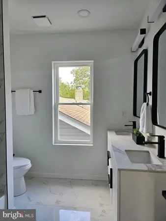a bathroom with a granite countertop sink a toilet and a mirror