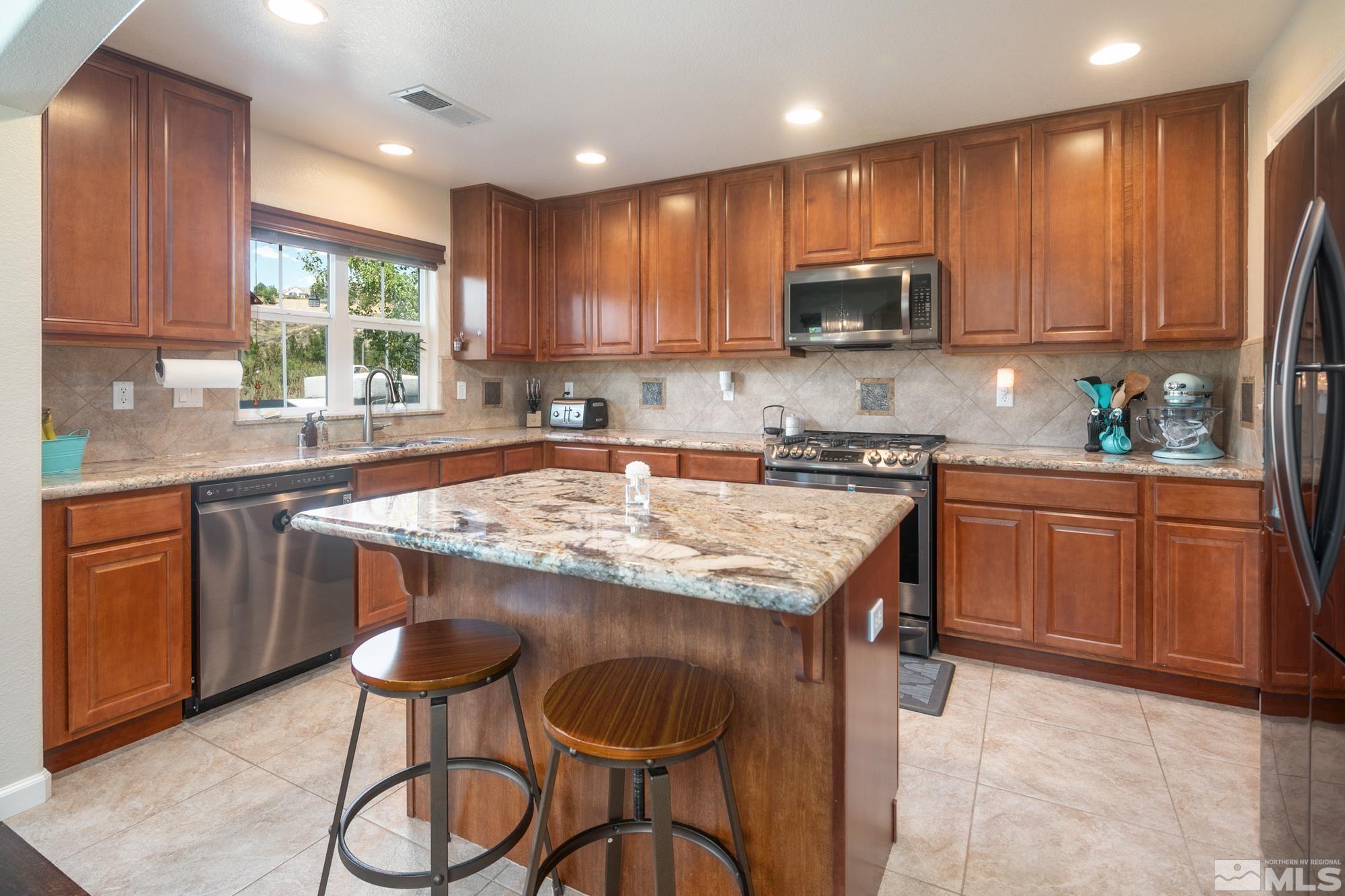 7665 Pebblestone Way Reno, NV 89523 - Photo 12 of 34 a kitchen with stainless steel appliances granite countertop wooden cabinets a stove top oven a sink and dishwasher