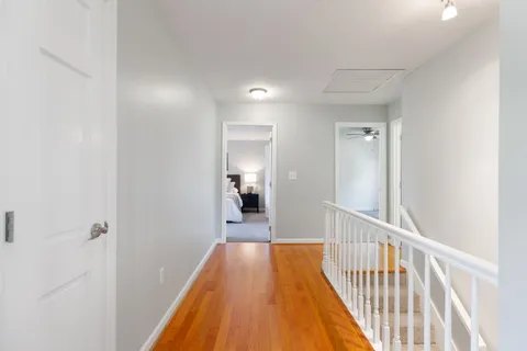 a view of a hallway with wooden floor and staircase
