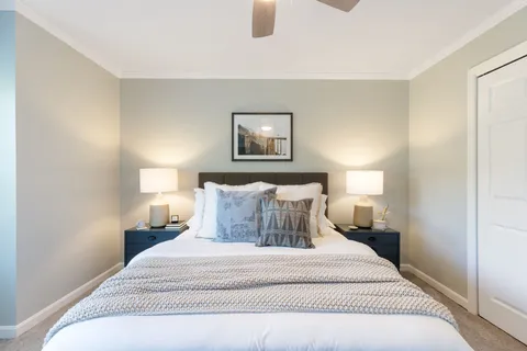 a bedroom with a bed and a potted plant on the dresser