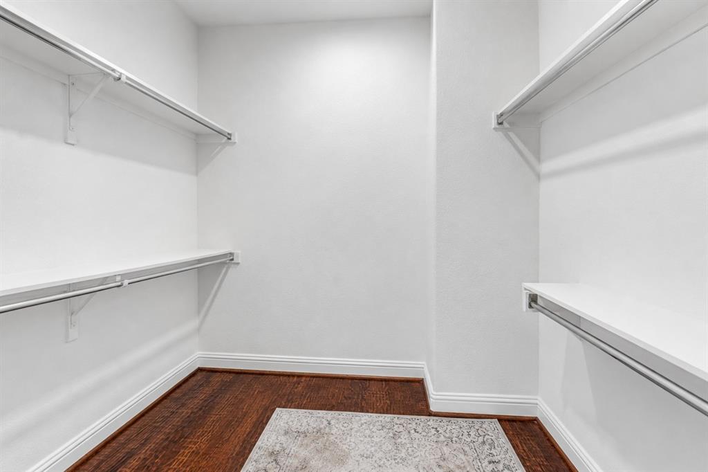 5744 Robbie Road Plano, TX 75024 - Photo 30 of 32 Walk-in closet featuring white shelving with chrome hanging rods, dark wood-finish flooring, and white baseboards