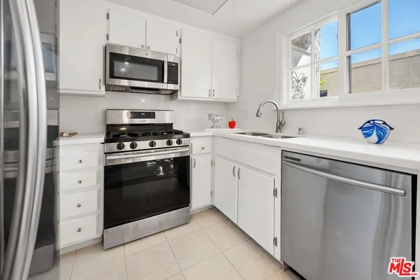 a kitchen with cabinets stainless steel appliances and sink