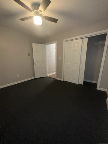 an empty room with wooden floor and fan