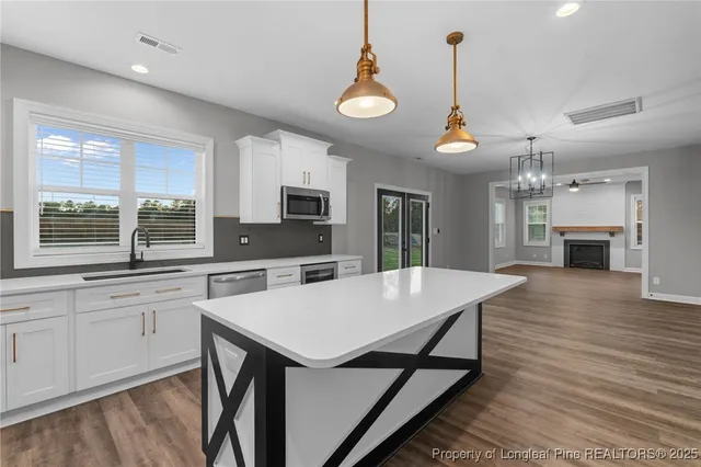 a large kitchen with kitchen island a stove a sink a center island and wooden floor