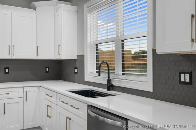 a kitchen with stainless steel appliances granite countertop a sink a stove and white cabinets