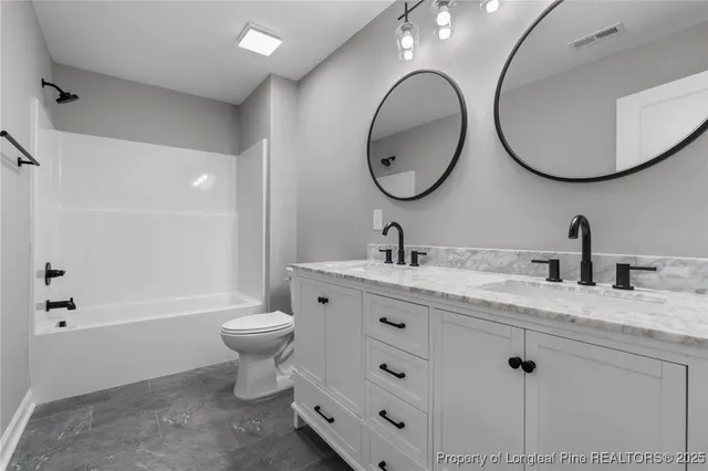 a bathroom with a granite countertop toilet a sink and a mirror