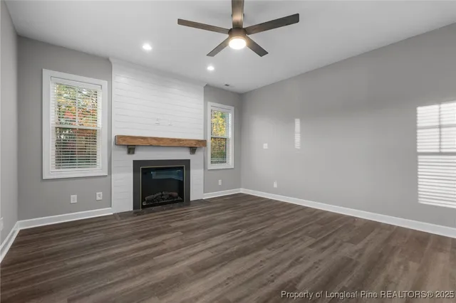 a view of an empty room with wooden floor fireplace and a window