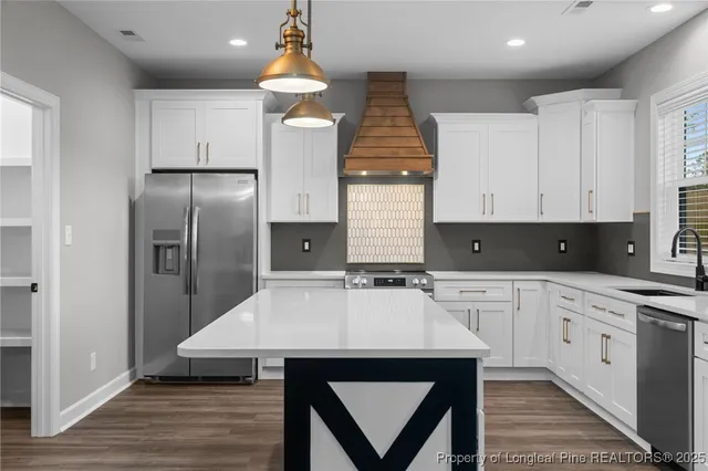 a kitchen with stainless steel appliances a sink a stove a refrigerator and cabinets