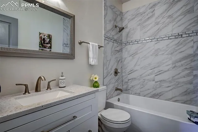 a bathroom with a granite countertop sink a toilet and bathtub