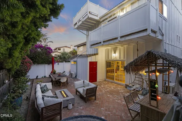 a view of a patio with couches table and chairs under an umbrella