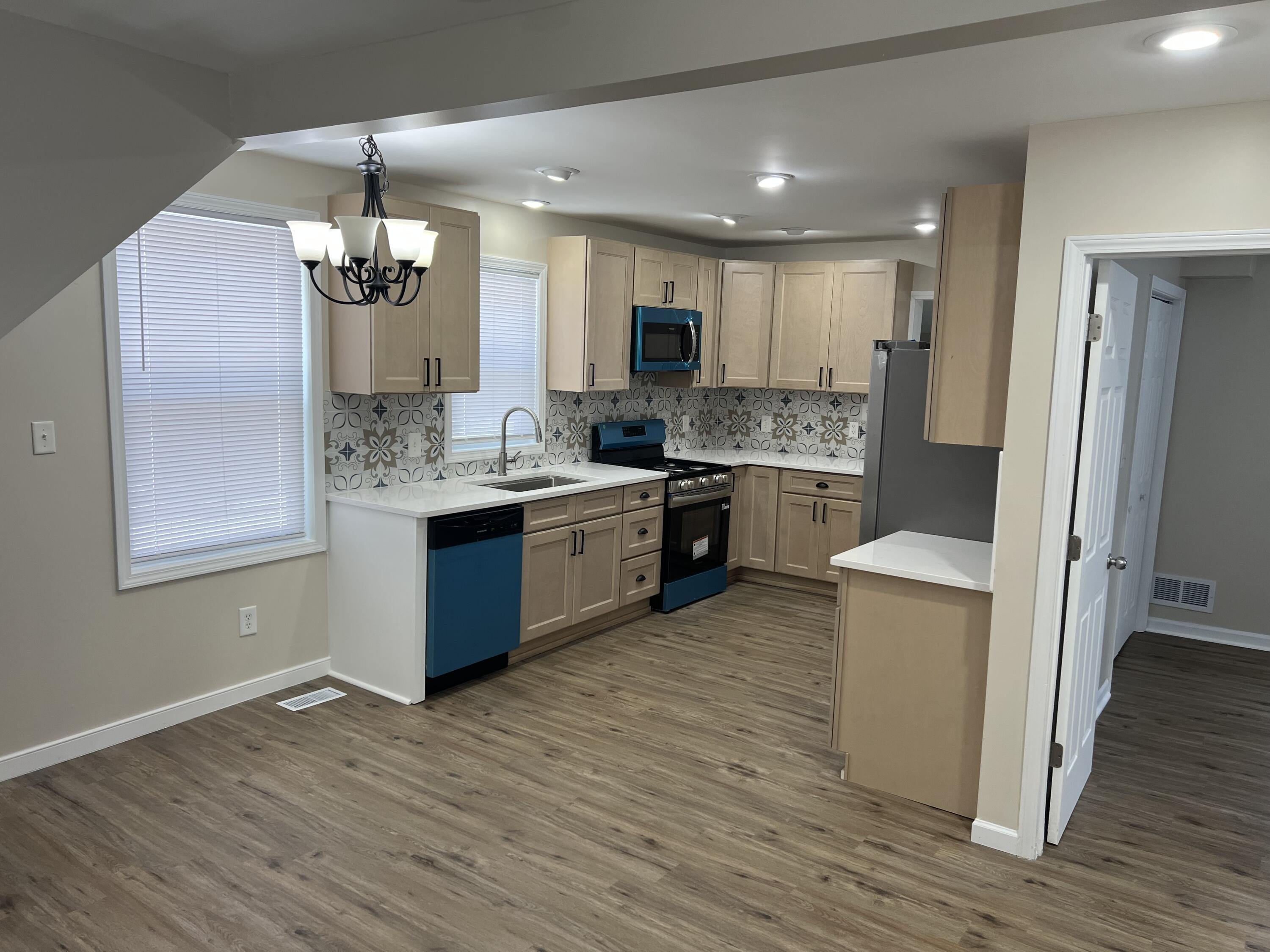 3851 Maple Street Hobart, IN 46342 - Photo 4 of 28 a large kitchen with a center island wooden floor stainless steel appliances and living room view