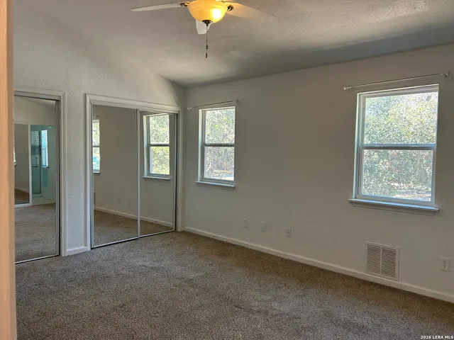 an empty room with windows and fan