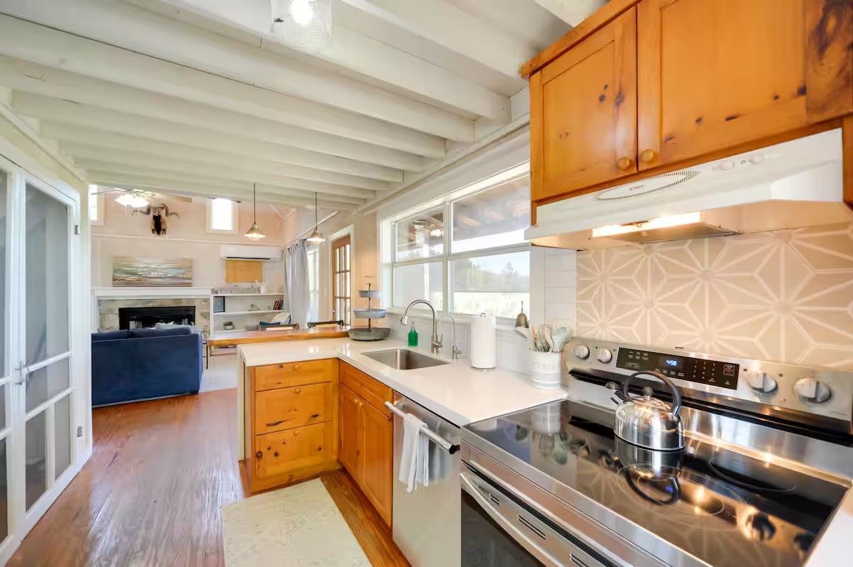 17 September Ridge Johnson City, TX 78636 - Photo 11 of 40 Kitchen featuring appliances with stainless steel finishes, a sink, under cabinet range hood, light wood-style flooring, and beam ceiling