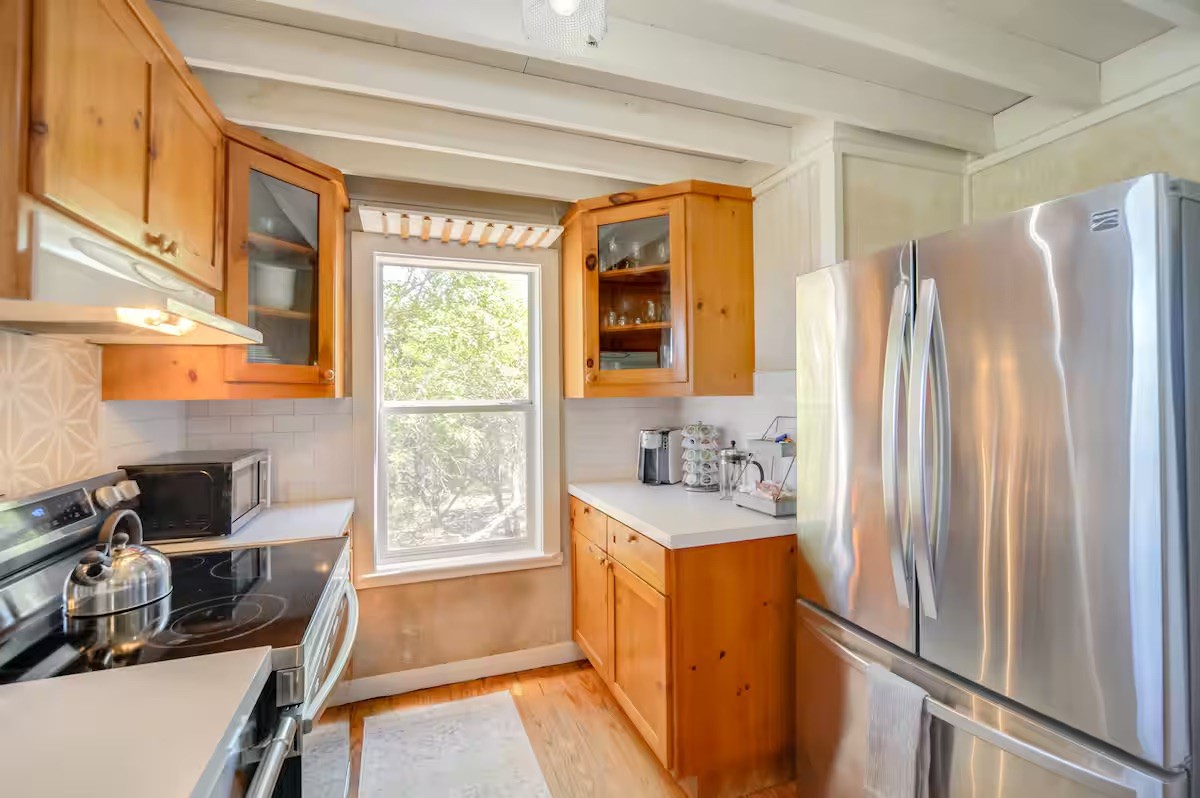 17 September Ridge Johnson City, TX 78636 - Photo 13 of 40 Kitchen featuring stainless steel appliances, under cabinet range hood, light wood-type flooring, light countertops, and beamed ceiling