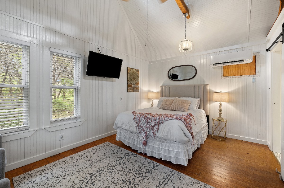 17 September Ridge Johnson City, TX 78636 - Photo 24 of 40 Bedroom with an AC wall unit, wood finished floors, lofted ceiling, multiple windows, and baseboards