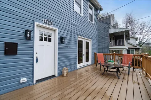 a backyard of a house with wooden floor chairs sofa and barbecue grill
