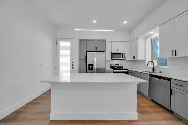 a kitchen with a refrigerator a sink and dishwasher with wooden floor