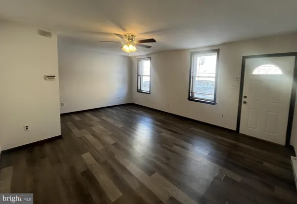 an empty room with wooden floor ceiling fan and window