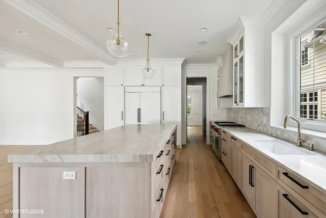 a large kitchen with granite countertop a large counter top a sink stainless steel appliances and cabinets