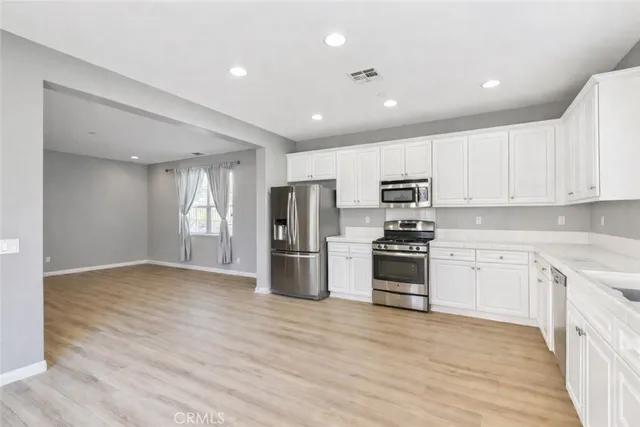 a kitchen with stainless steel appliances granite countertop a stove top oven a refrigerator a sink and a dining table with wooden floor