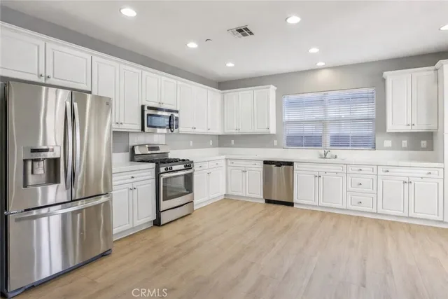a kitchen with granite countertop white cabinets and stainless steel appliances