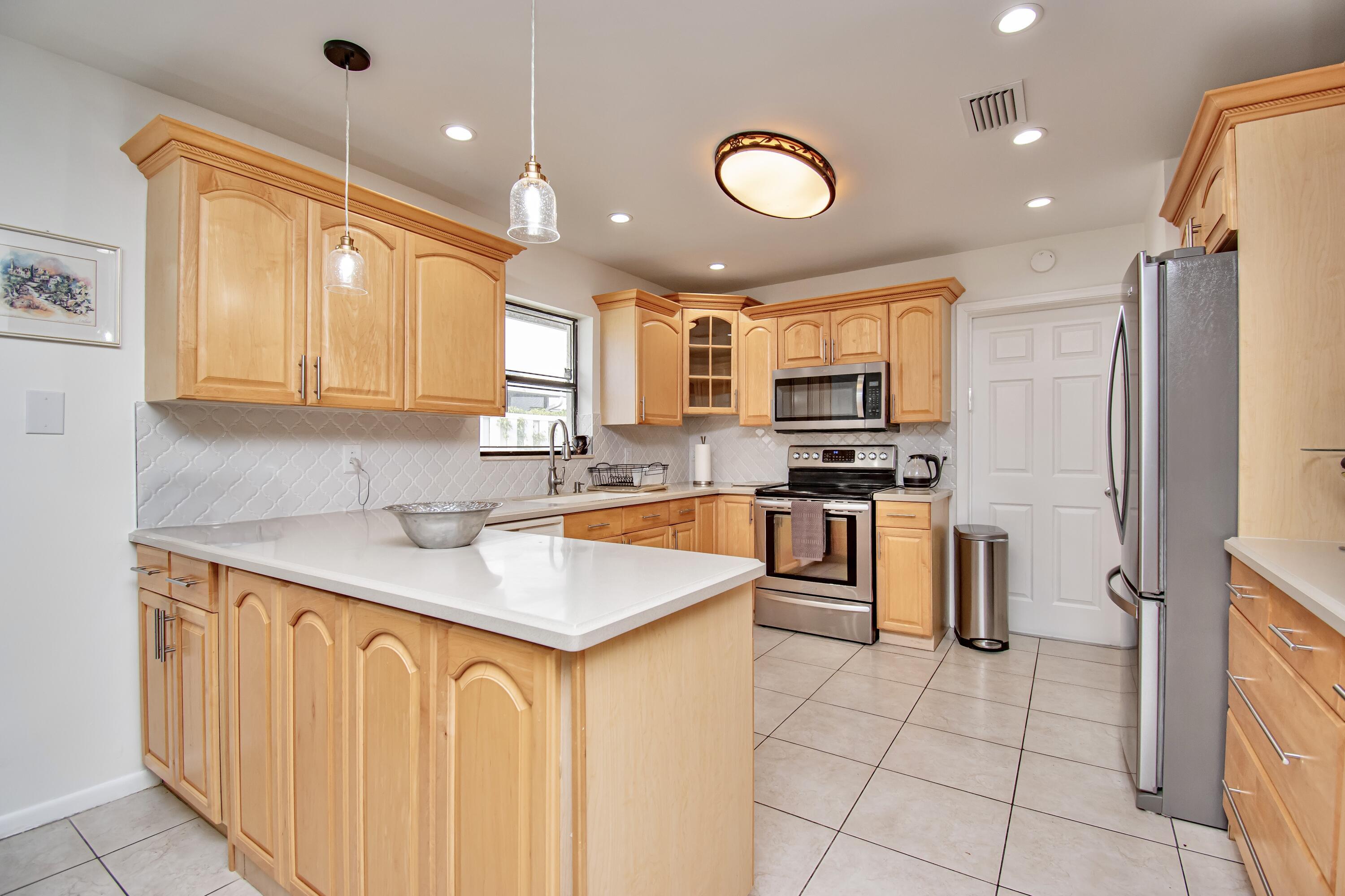 7838 Cypress Crescent Boca Raton, FL 33433 - Photo 11 of 24 a kitchen with stainless steel appliances granite countertop a sink stove and refrigerator