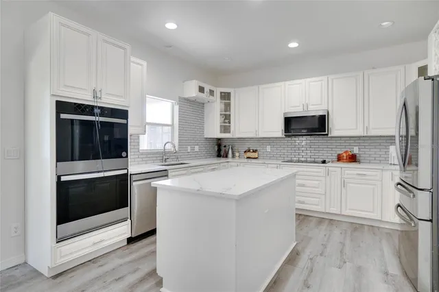 a kitchen with white cabinets and stainless steel appliances
