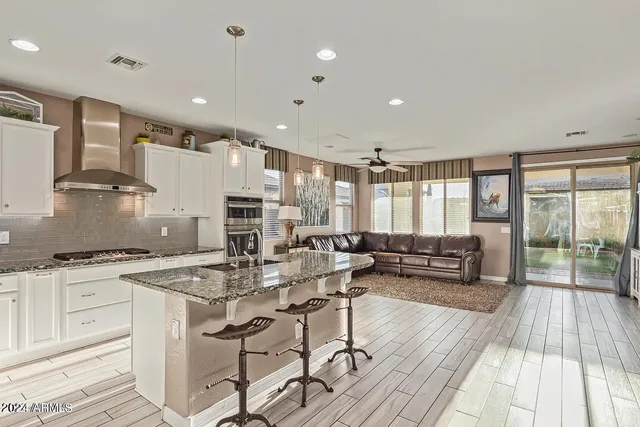 a kitchen with stainless steel appliances granite countertop a stove a sink dishwasher and a dining table with wooden floor