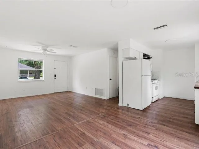 an empty room with wooden floor cabinet and windows