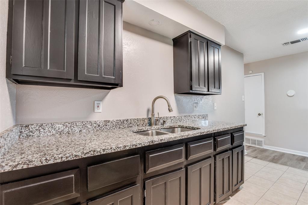 735 Middale Road Duncanville, TX 75116 - Photo 9 of 25 a sink with granite countertop wooden cabinets