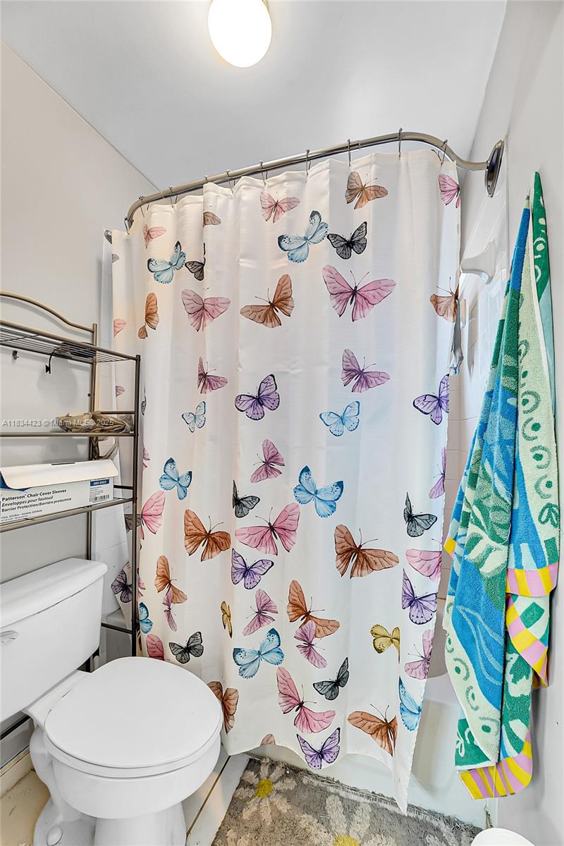 1303 West 6th Street Riviera Beach, FL 33404 - Photo 13 of 33 a white toilet sitting next to a bathroom sink and a shower curtain