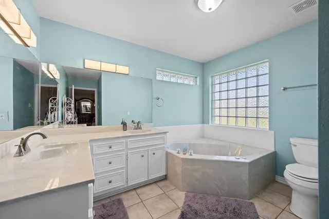 a bathroom with a granite countertop toilet a sink a mirror a bathtub and window