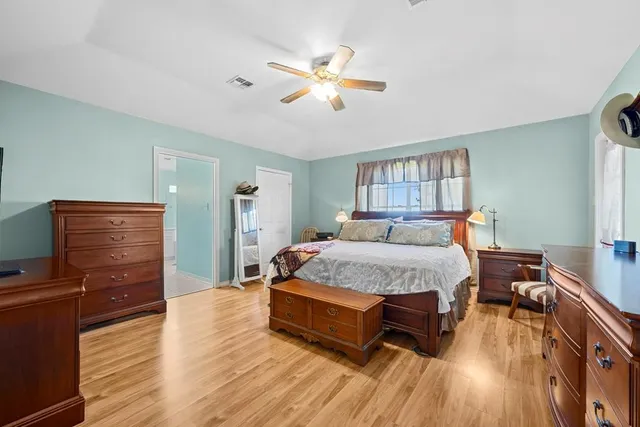 a spacious bedroom with a bed and wooden floor