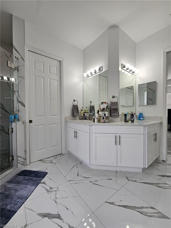 4340 Golden Gate Boulevard East Naples, FL 34120 - Photo 19 of 41 Full bath with light marble finish floors, double vanity, and a marble finish shower
