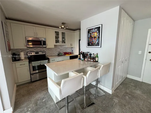 a kitchen with stainless steel appliances a stove a sink a microwave a refrigerator and cabinets