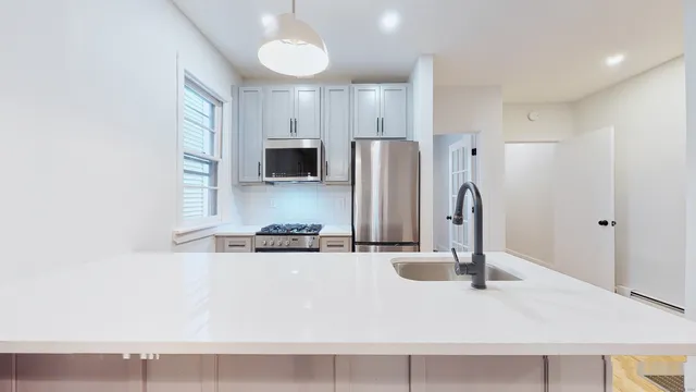 a kitchen with stainless steel appliances granite countertop a sink and a refrigerator
