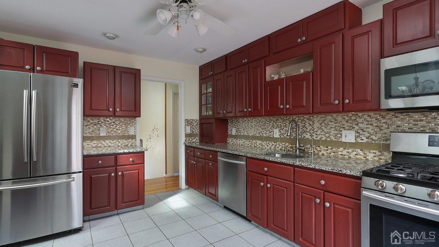 20 Peake Road Edison, NJ 08837 - Photo 11 of 34 a kitchen with stainless steel appliances granite countertop a stove top oven a refrigerator and a sink with wooden cabinets