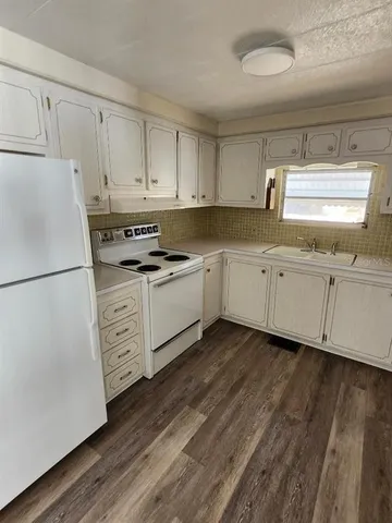 a kitchen with granite countertop white cabinets and white appliances