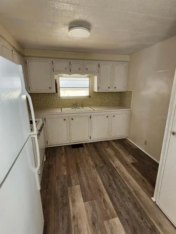 a room with granite countertop white cabinets and wooden floor