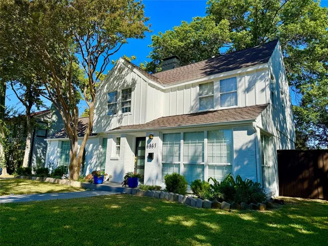 a front view of a house with a garden and trees