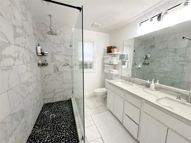a bathroom with a double vanity sink toilet mirror and shower