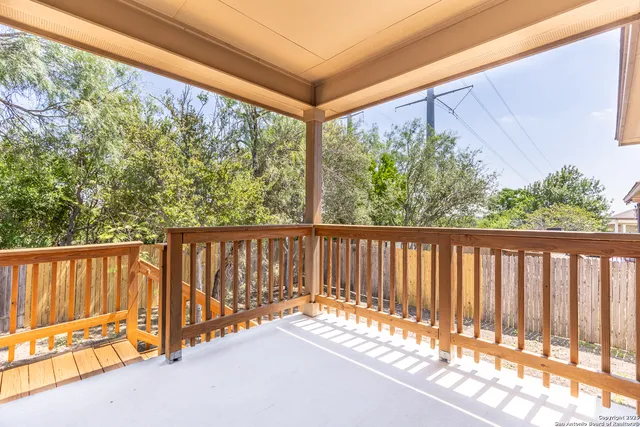 a view of a backyard with large trees and wooden fence