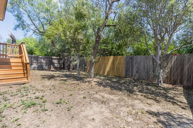 a view of an house with backyard and trees